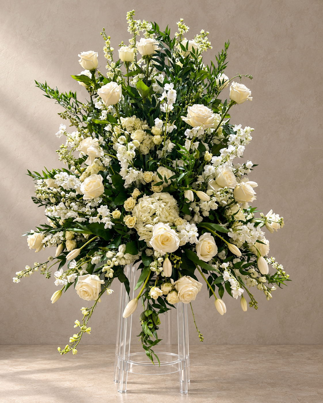 White Altar standing arrangement with ivory roses, hydrangeas, tulips and white flowering sprays on a clear acrylic pedestal