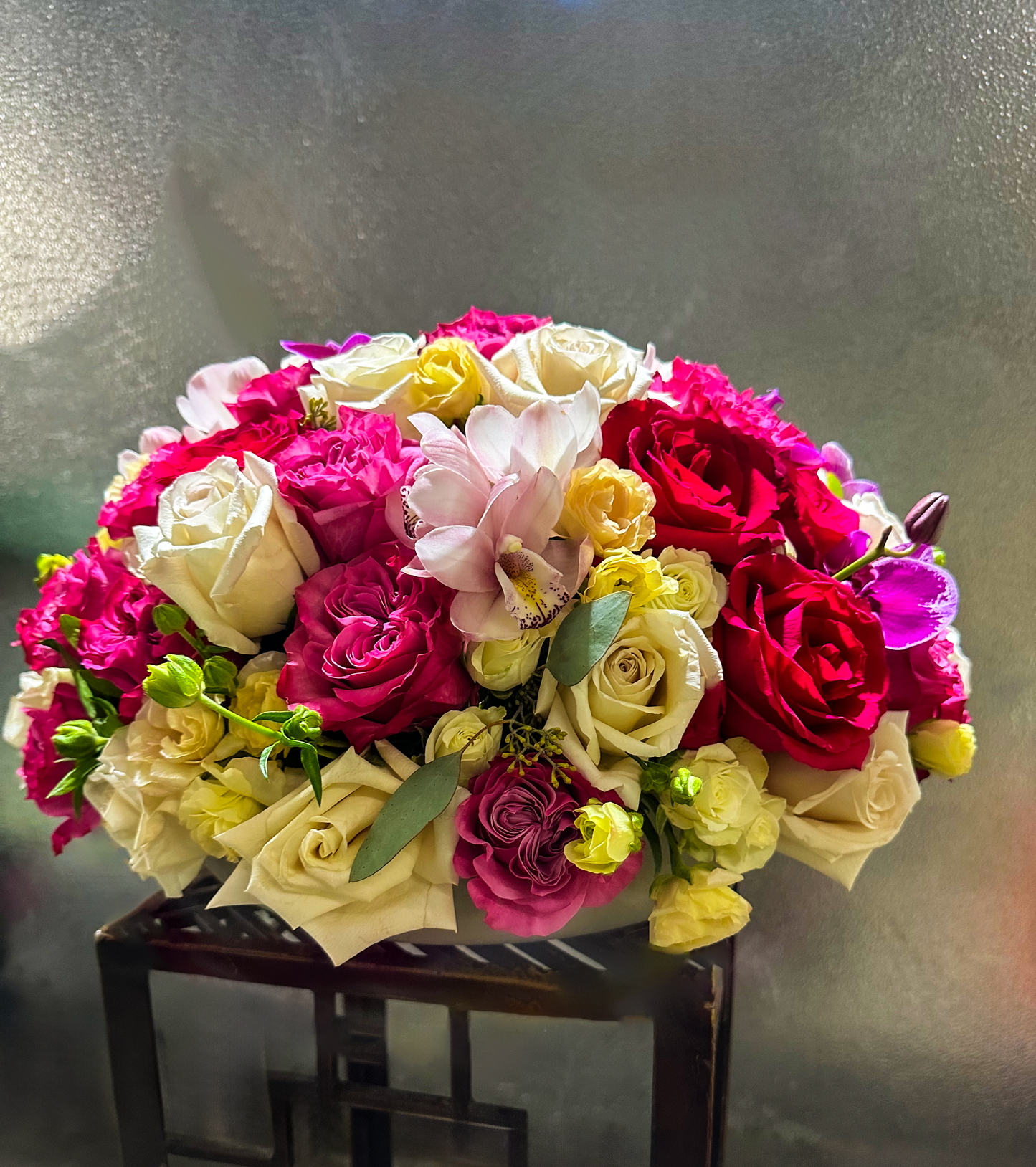 Elegant floral arrangement with vibrant pink, red, and white roses, complemented by delicate orchids and lush greenery, creating a luxurious arrangement for events or special occasions by VIP Floristry in Houston.
