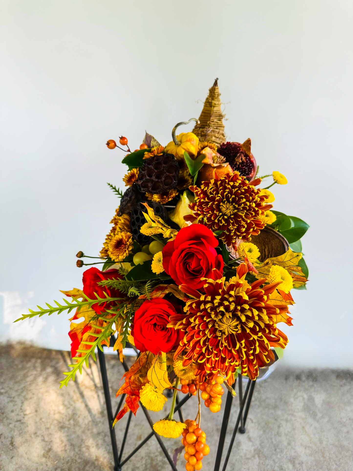 Elegant cornucopia-style floral centerpiece highlighting vivid red roses, orange chrysanthemums, and fall-inspired foliage, crafted with premium elements by VIP Floristry. Ideal for upscale seasonal décor and events in Houston.