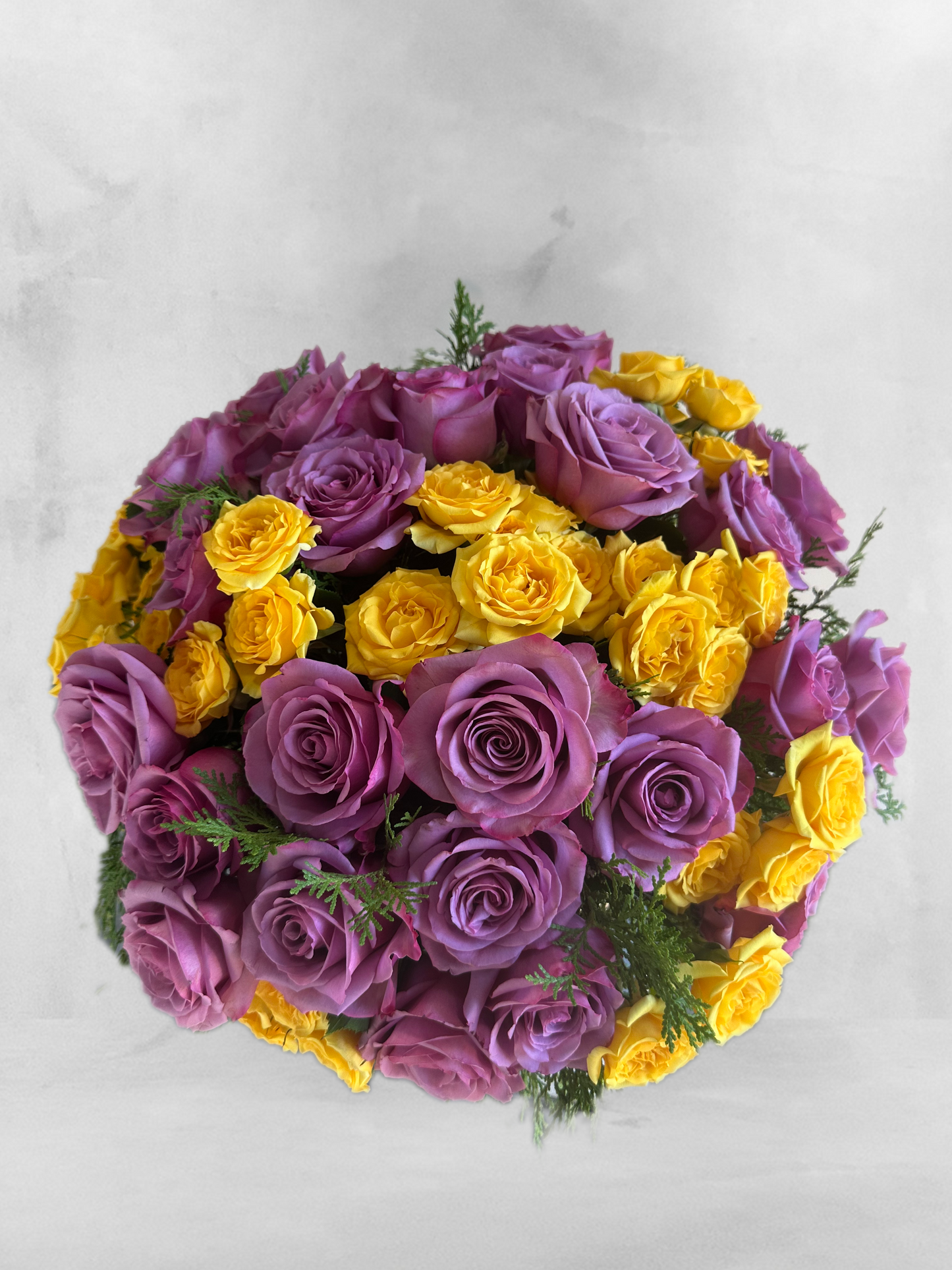 Top view of the luxury floral arrangement with lavender and yellow roses, accented by greenery, in a clear glass bowl. This arrangement adds a refined elegance to any setting, catering to high-end Houston events.