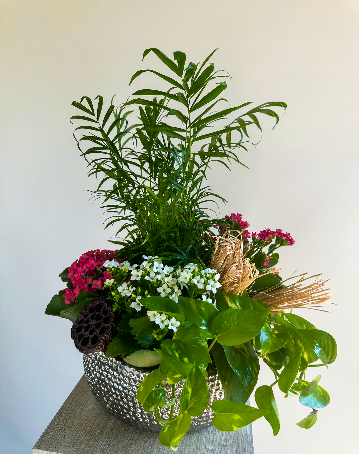 Elegant silver bowl with mixed green and flowering plants, including pink and white kalanchoes, lush pothos, and decorative elements, perfect for high-end interior decoration in Houston spaces.