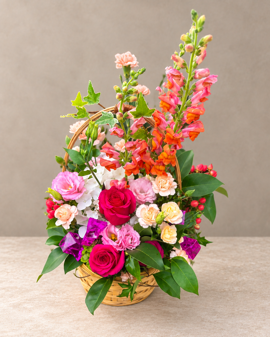 Alternate view of the Sweet Girl arrangement with pink roses, orange snapdragons, white hydrangea and colorful accents in a woven basket.
