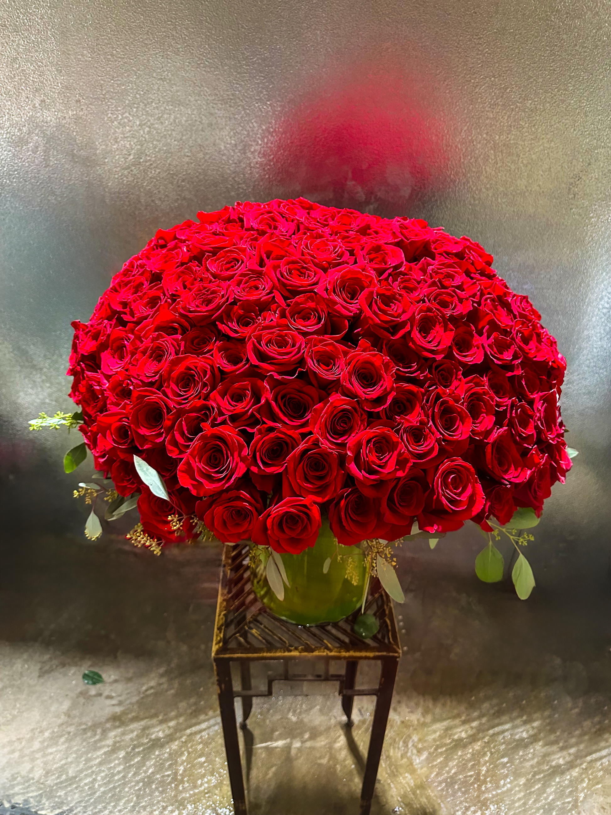 Luxurious bouquet of vibrant red roses in a green vase, showcasing VIP Floristry's elegant floral design services in Houston.