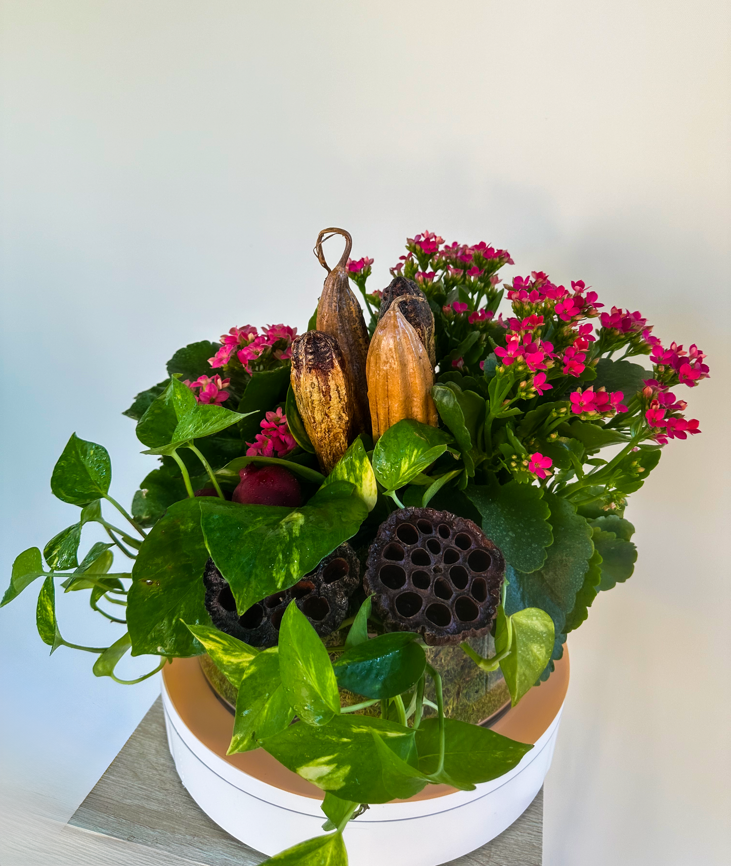 Close-up of a vibrant floral display with trailing pothos, pink kalanchoe flowers, and dried natural elements, adding texture to sophisticated decor by VIP Floristry in Houston.