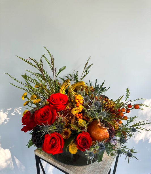 Vibrant autumn-inspired floral arrangement with red roses, yellow chrysanthemums, berries, and greenery, crafted by VIP Floristry for luxury seasonal arrangements in Houston.