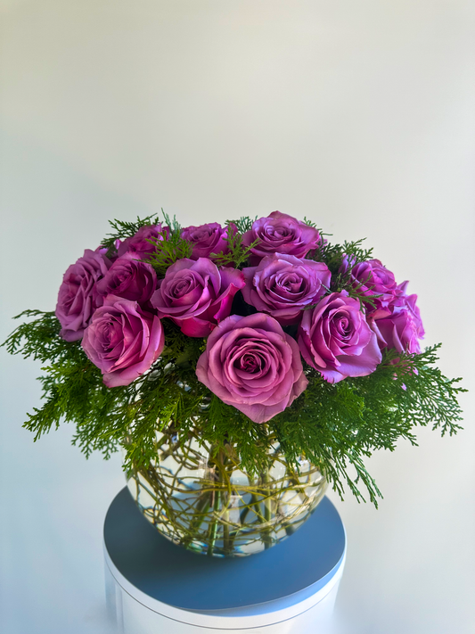 Elegant display of lavender roses and green foliage in a round glass vase, perfect for upscale floral arrangements in Houston by VIP Floristry.