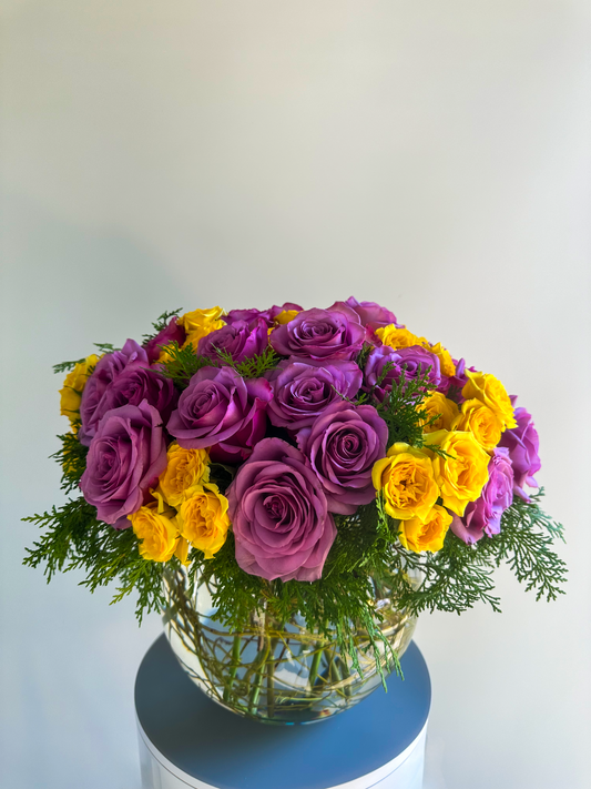 Elegant floral arrangement in a bowl, featuring a beautiful mix of lavender and yellow roses with lush greenery. This design brings a vibrant yet soft touch, perfect for luxury events in Houston.