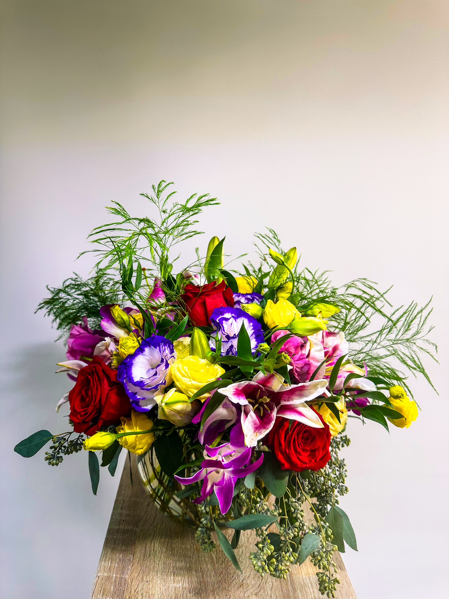 Stunning bouquet of colorful flowers including red roses, purple lisianthus, and lilies, arranged in a clear vase, crafted by VIP Floristry in Houston.