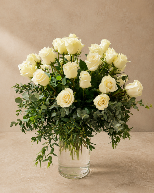White Rose Forest arrangement with tiered white roses and cascading eucalyptus greenery in a tall clear glass cylinder vase.